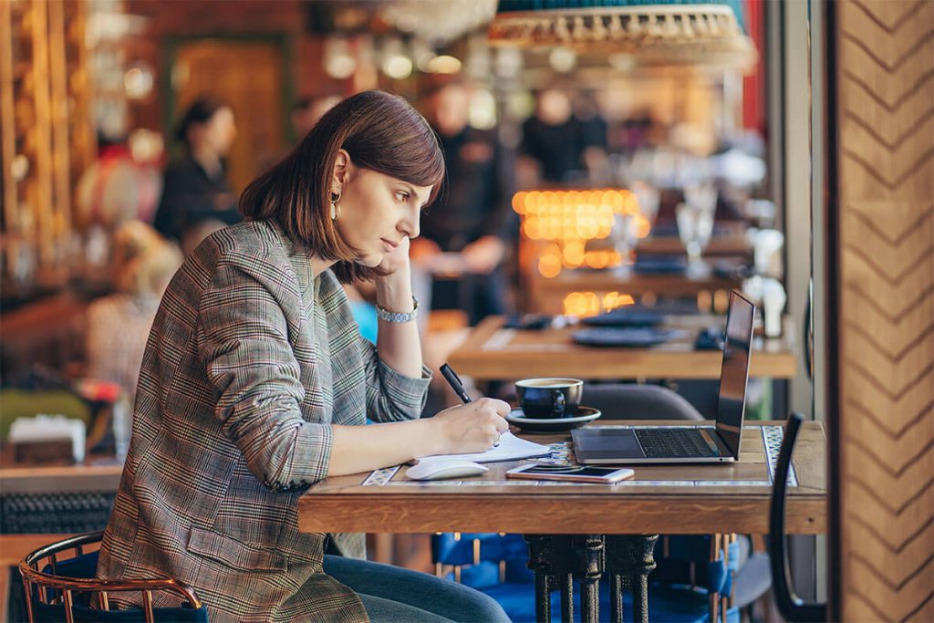 Frau sitzt in einem Café und arbeitet am Laptop