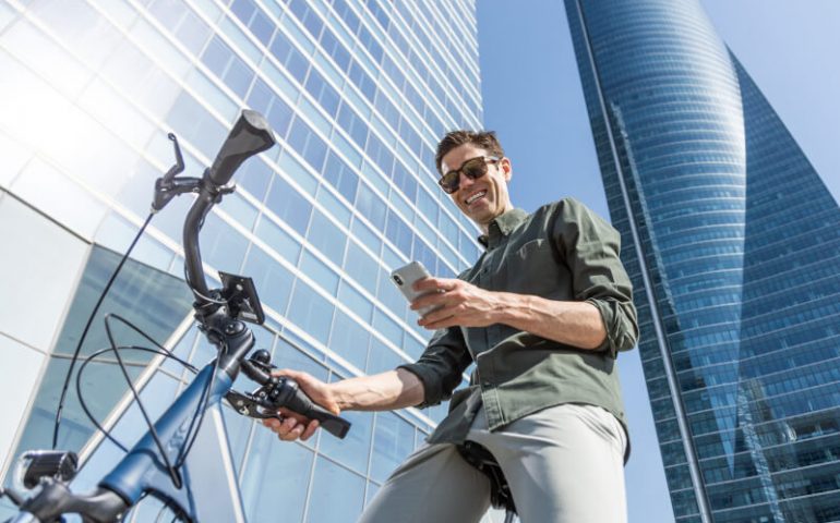 Mann auf E-Bike zwischen hohen Gebäuden