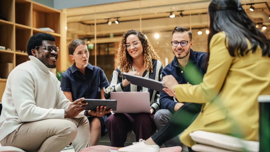 Meeting eines diversen, lachenden Teams in Businesskleidung
