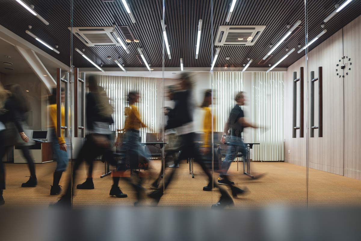 Viele Menschen laufen hektisch im Büro hin und her