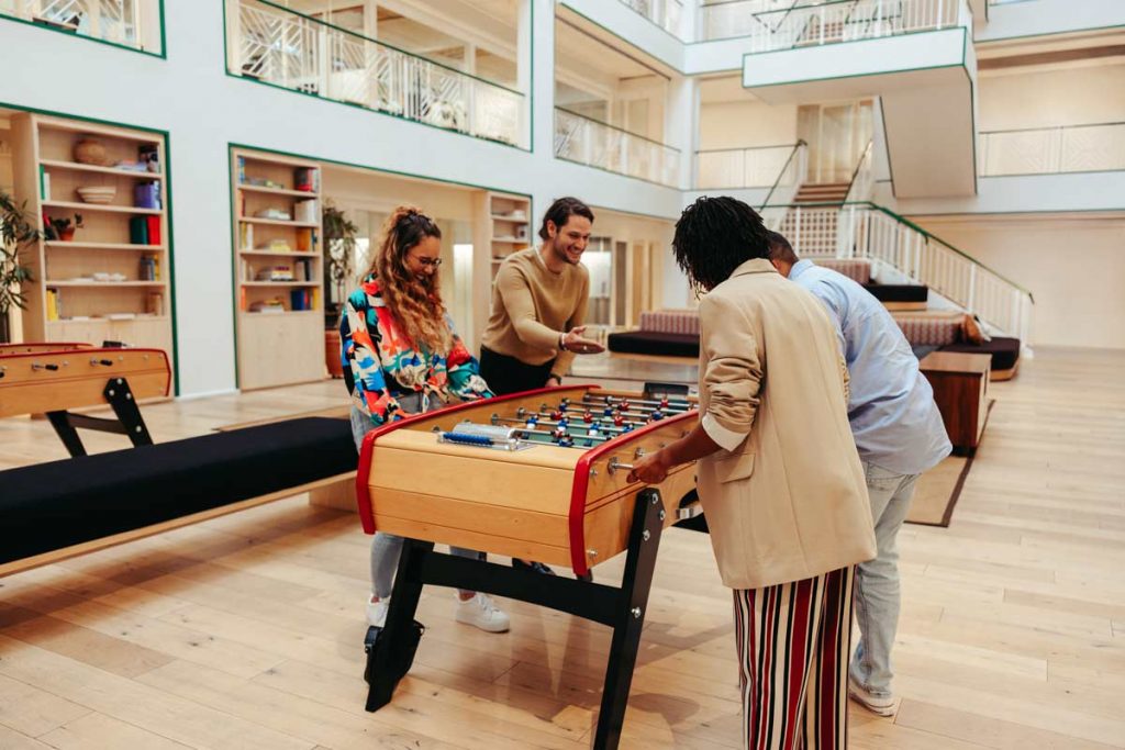 Kolleg:innen spielen gemeinsam Tischkicker im Büro