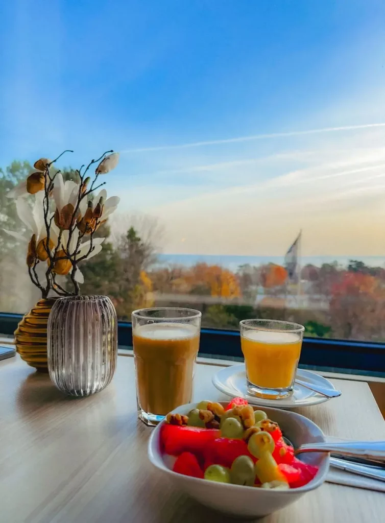 Obstsalat, Kaffee und Saft auf einem Tisch - im Hintergrund die Ostsee und Bäume